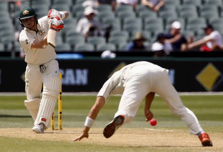 Australia's captain Steve Smith (L) watches as New Zealand's Doug Bracewell dives on the pitch to stop the ball during the second day of the third cricket test match at the Adelaide Oval, in South Australia, November 28, 2015. REUTERS/David Gray