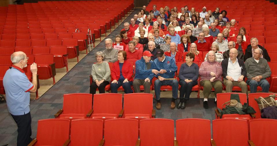 John Hampu, left, speaks to former Alliance Aviator Marching Band members seated for a group photo on Jan. 28 at Alliance High School for former band leader John E. Weitzel. The photo was taken as a special gift for Weitzel's 99th birthday.