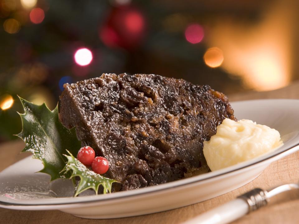 A slice of Christmas pudding with a scoop of brandy butter on the side.