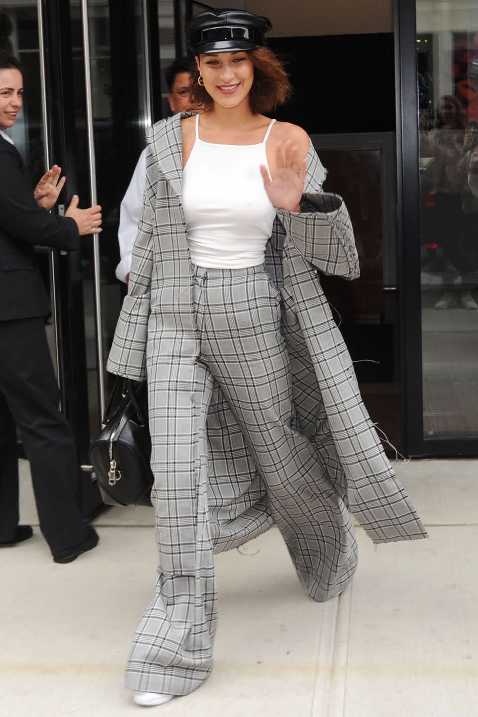 <p>In an oversized gray plaid trench and trousers from Zimmermannn, white tank top, white sneakers and conductor hat while out in NYC.</p>