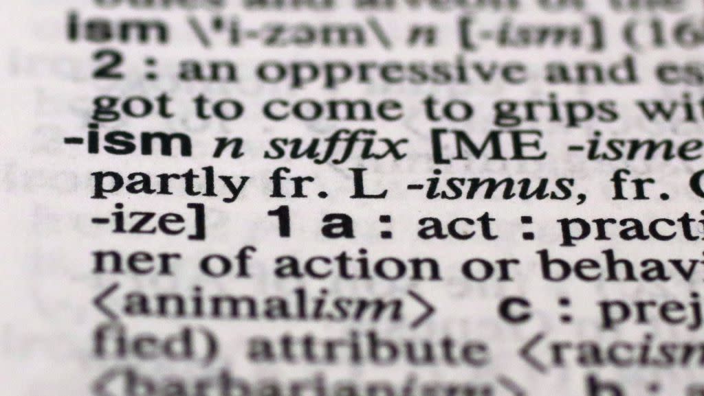 The suffix "ism" is photographed in Merriam-Webster's Collegiate Dictionary,