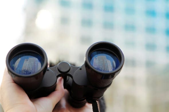 Businessman searching  office buildings with binoculars.