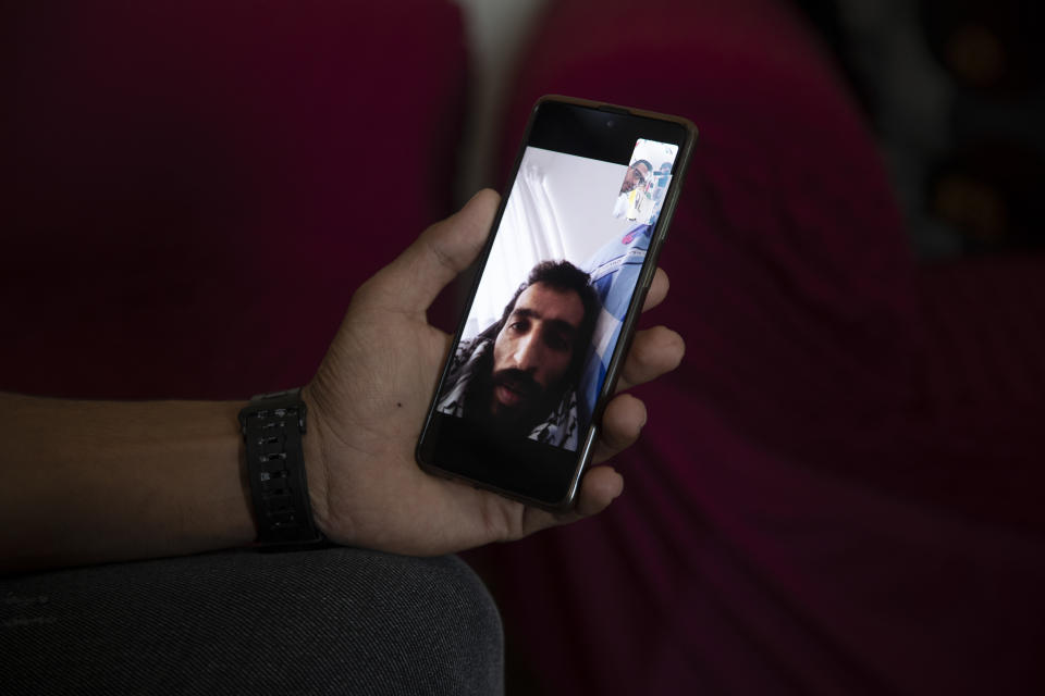 Khaled Fasfous shows a photo on his phone of his brother Kayed Fasfous a Palestinian prisoner who has been on hunger strike for 120 days to protest being detained without charge by Israel, in the village of Dora, near the West Bank town of Hebron, Thursday, Nov. 11, 2021. Israel faced growing calls on Thursday to release five Palestinians who have been on hunger strike for weeks to protest a controversial policy of holding them indefinitely without charge, including one who has been fasting for 120 days and is in severe condition. (AP Photo/Majdi Mohammed)