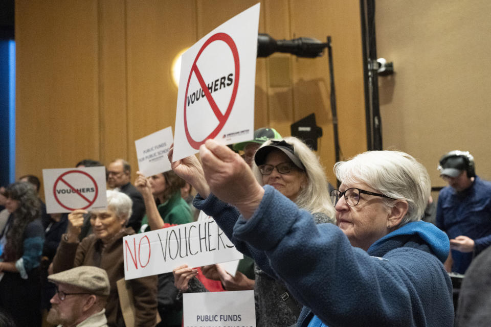 FILE - Mirabelle Stoedter holds a sign against school vouchers during a news conference Tuesday, Nov. 28, 2023, in Nashville, Tenn. Using public funds to pay for religious school tuition — especially with generous income limits or none at all — remains controversial as proponents gain ground in Republican-majority states. (AP Photo/George Walker IV, File)