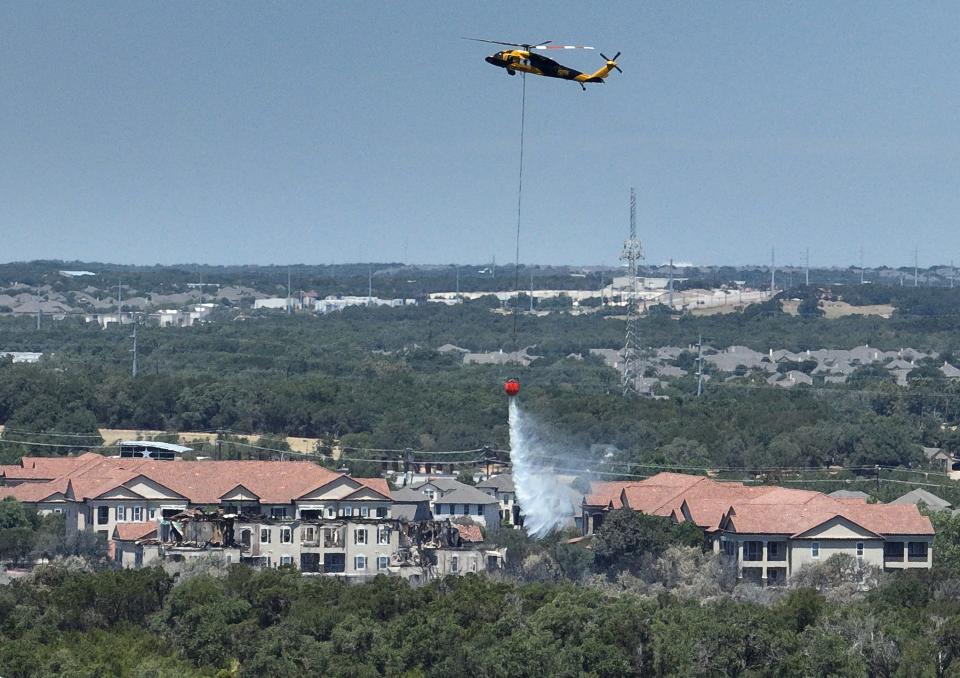 A firefighting helicopter works at a brush fire that destroyed a building at Bexley Apartments at Silverado in Cedar Park on Wednesday August 9, 2023.