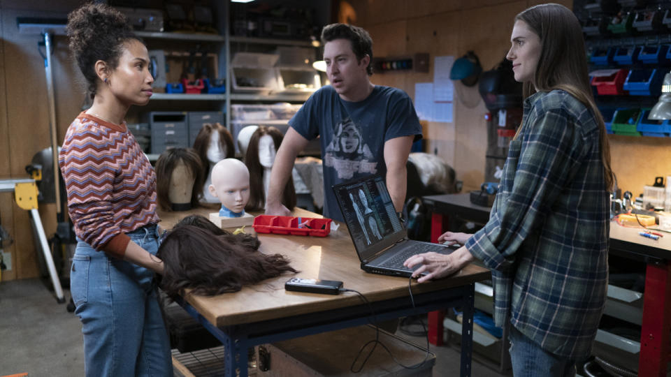 Jen Van Epps, Brian Jordan Alvarez, and Allison Williams stand around a worktable in discussion in M3GAN.