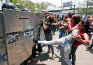 <p>A woman kicks at a riot police shield as relatives of prisoners wait to hear news about their family members imprisoned at a police station where a riot broke out, in Valencia, Venezuela, Wednesday, March 28, 2018. In a state police station housing more than one hundred prisoners, a riot culminated in a fire, requiring authorities to open a hole in a wall to rescue the inmates. (Photo: Juan Carlos Hernandez/AP) </p>