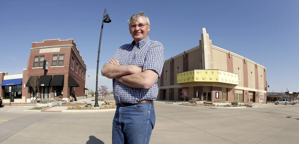 In this photo taken April, 18, 2014, Mayor Bob Dixson stands with a soon-to-be completed community theater at right, and the only downtown building to survive a massive tornado in Greensburg, Kan. Seven years after an EF-5 tornado destroyed most of the community of 1,500, Dixson believes most of the town's current 850 residents are ready to move on and deal with the same sort of problems that plague most rural communities. (AP Photo/Charlie Riedel)