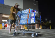 John Beezley, of Bonham, carts out several cases of water after learning that a boil water notice was issued for the entire city of Houston on Sunday, Nov. 27, 2022, at Walmart on S. Post Oak Road in Houston. Beezley just arrived in town with his wife, who is undergoing treatment starting tomorrow at M.D. Anderson Cancer Center, where they are staying in a camping trailer. They turned on the television after settling in and saw that a boil water notice had been issued. Beezley decided to go out immediately fearing that by tomorrow people would be buying up all of the available water. (Mark Mulligan/Houston Chronicle via AP)