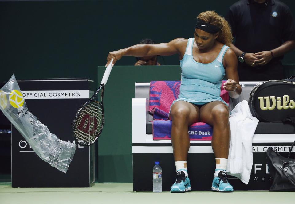 Williams of the U.S. takes the plastic cover off a new racquet after smashing her first one during her WTA Finals singles semi-finals tennis match against Wozniacki of Denmark at the Singapore Indoor Stadium