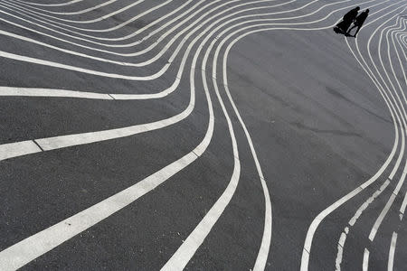 Residents walk over a landscape feature in Superkilen, a park designed as part of an urban design renewal scheme that runs along the side of Mjolnerparken, a housing estate that features on the Danish government's "Ghetto List", in Copenhagen, Denmark, May 9, 2018. REUTERS/Andrew Kelly