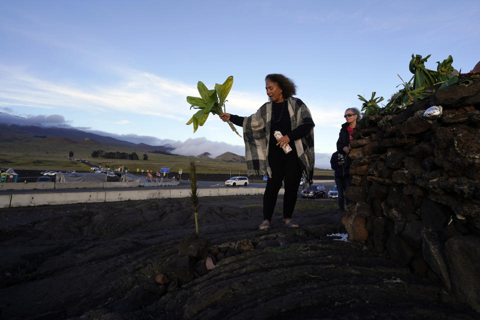 Illona Ilae, a Native Hawaiian from Kailua-Kona, Hawaii, sings as she leaves an offering in front an alter below the Mauna Loa volcano as it erupts Thursday, Dec. 1, 2022, near Hilo, Hawaii. Glowing lava from the world's largest volcano is a sight to behold, but for many Native Hawaiians, Mauna Loa's eruption is a time to pray, make offerings and honor both the natural and spiritual worlds. (AP Photo/Gregory Bull)