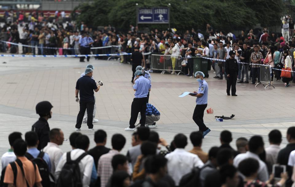 People look on as police officers investigate at the scene after a knife attack at a railway station in Guangzhou, Guangdong province May 6, 2014. Six people were wounded in a knife attack at a railway station in the southern Chinese city of Guangzhou on Tuesday, police said, the latest in a series of such assaults that have raised jitters around the country. REUTERS/Stringer (CHINA - Tags: CIVIL UNREST CRIME LAW TRANSPORT) CHINA OUT. NO COMMERCIAL OR EDITORIAL SALES IN CHINA