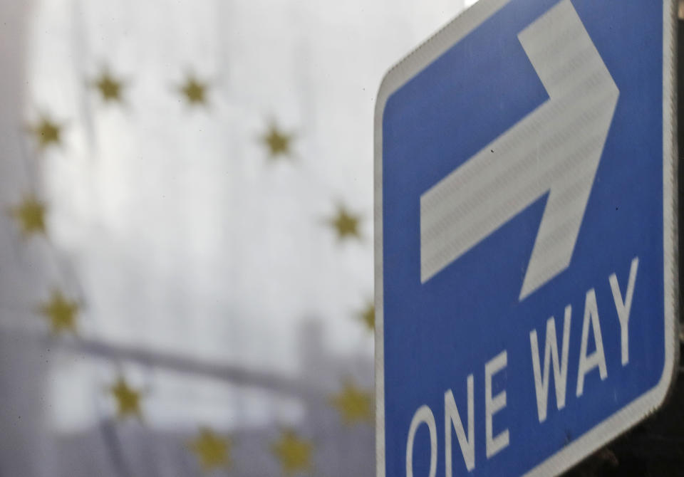 The EU flag hangs from Europa House behind a signpost in London, Tuesday, Sept. 29, 2020. Britain has entered a crucial week of post-Brexit talks with the European Union by rejecting the EU’s demand that it drop plans to breach the legally binding agreement it signed on its departure from the bloc. The EU told British Prime Minister Boris Johnson to brace for a legal fight. (AP Photo/Frank Augstein)