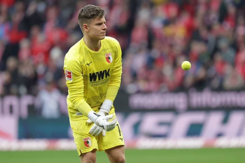 Augsburg goalkeeper Finn Dahmen throws back a tennis balls thrown onto the pitch by spectators in protest against the German Football League's (DFL) plans to bring in investors, during the German Bundesliga soccer match between FSV Mainz 05 and FC Augsburg at the Mewa Arena. Jürgen Kessler/dpa