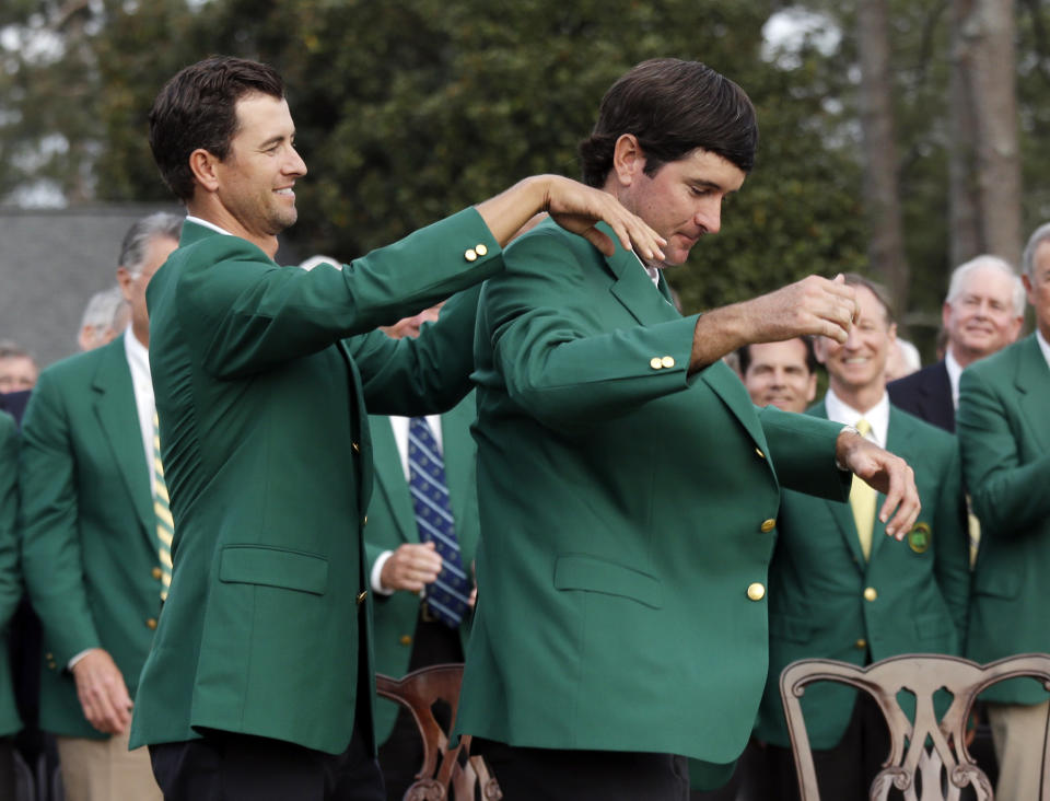 Defending Masters' champion Adam Scott, of Australia, helps Bubba Watson, right, with his green jacket after winning the Masters golf tournament Sunday, April 13, 2014, in Augusta, Ga. (AP Photo/Darron Cummings)
