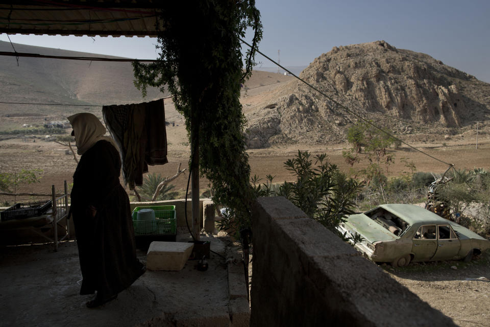 A Palestinian woman stands at her balcony in Jiftlik area of Jordan Valley in the West Bank, along the border with Jordan, Thursday, Jan. 2, 2014. A senior Israeli Cabinet minister and more than a dozen hawkish legislators poured cement at a construction site in a settlement in the West Bank's Jordan Valley on Thursday, in what they said was a message to visiting U.S. Secretary of State John Kerry that Israel will never relinquish the strategic area. (AP Photo/Oded Balilty)