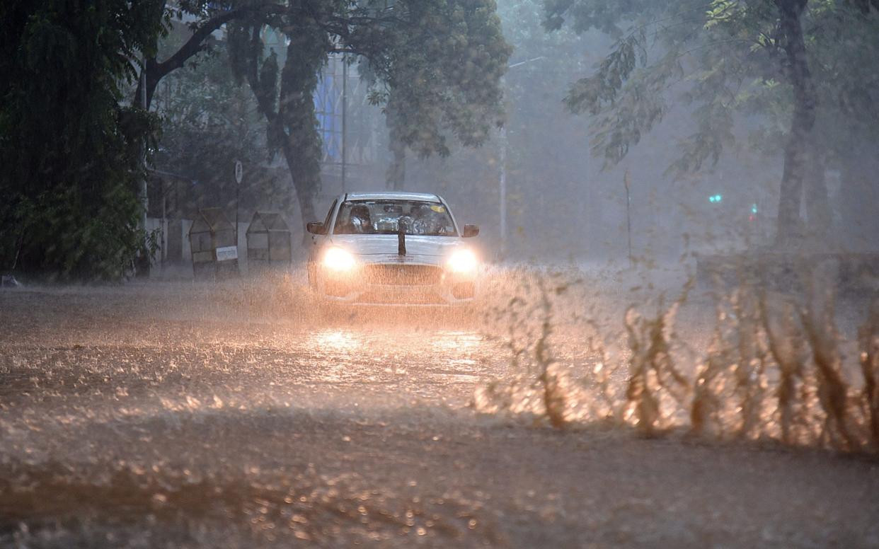 Commuters drive through a waterlogged road amidst heavy rains in Mumbai on May 17, 2021, as Cyclone Tauktae, packing ferocious winds and threatening a destructive storm, surge bore down on India,