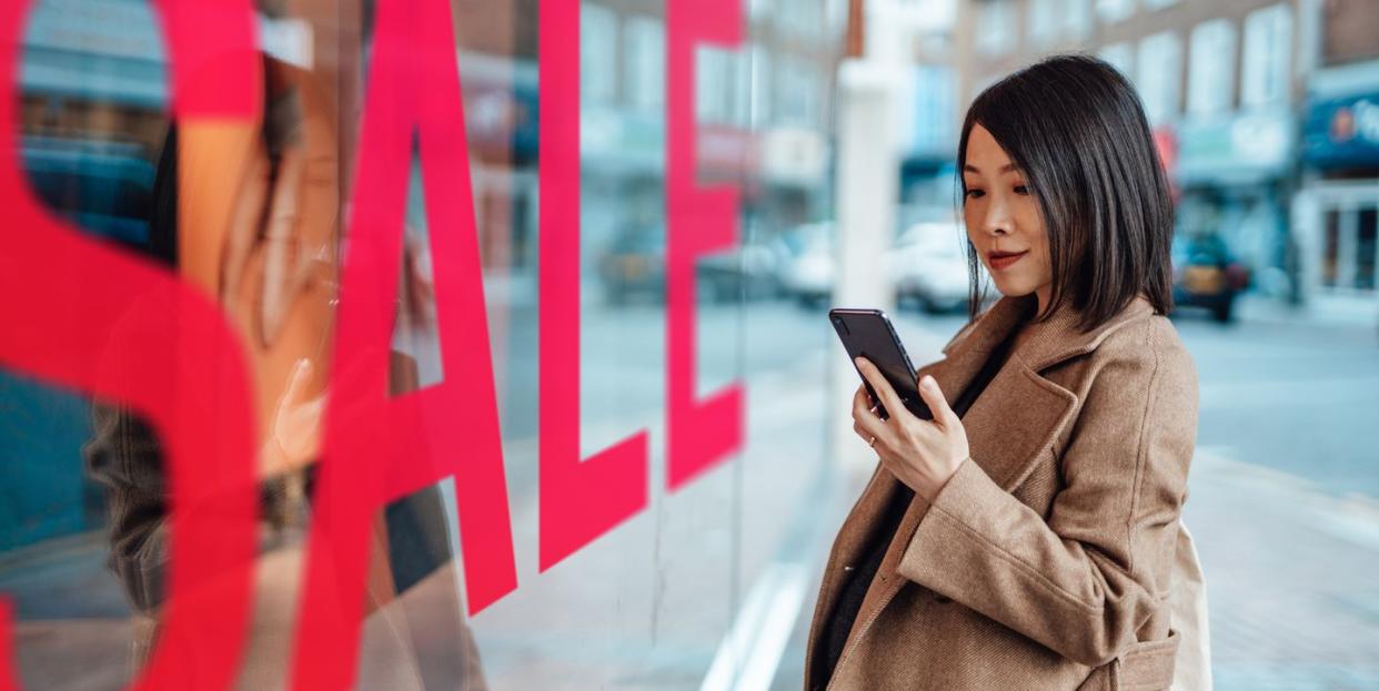 young woman window shopping on street in city