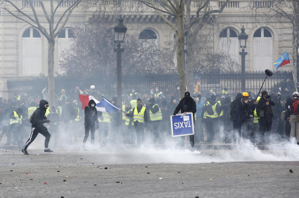 Yellow vests demonstrators damage urban road signs, Saturday, March 16, 2019 in Paris. French yellow vest protesters clashed Saturday with riot police near the Arc de Triomphe as they kicked off their 18th straight weekend of demonstrations against President Emmanuel Macron. (AP Photo/Christophe Ena)