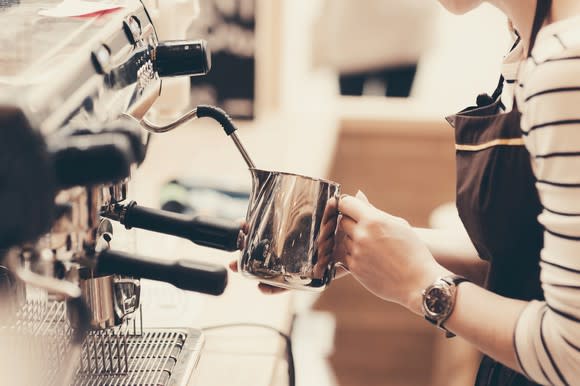 A barista froths milk on an espresso machine.