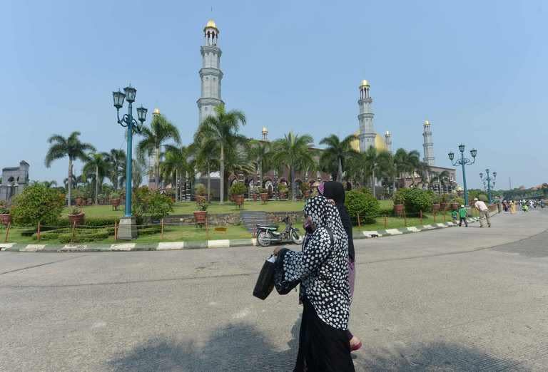 Indonesian women walk within the grounds of the Golden dome mosque in Depok, Jakarta, on May 5, 2013. As many in the burgeoning middle class spend their new-found wealth on Western brands, a backlash is growing among others who also have money but fear Indonesian Muslim culture is drowning in a sea of Starbucks and Coke