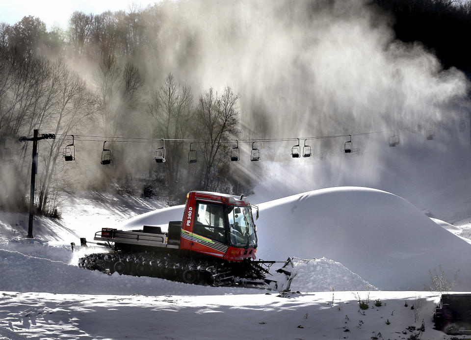 Snow billows from a snowmaker, Tuesday, Nov. 12, 2019, creating piles as Tom Roesler, mountain manager at Mount La Crosse in La Crosse, Wis., spreads it out. Pending weather conditions, Mount La Crosse staff are hoping to open the ski area before the end of the month. (Peter Thomson/La Crosse Tribune via AP)