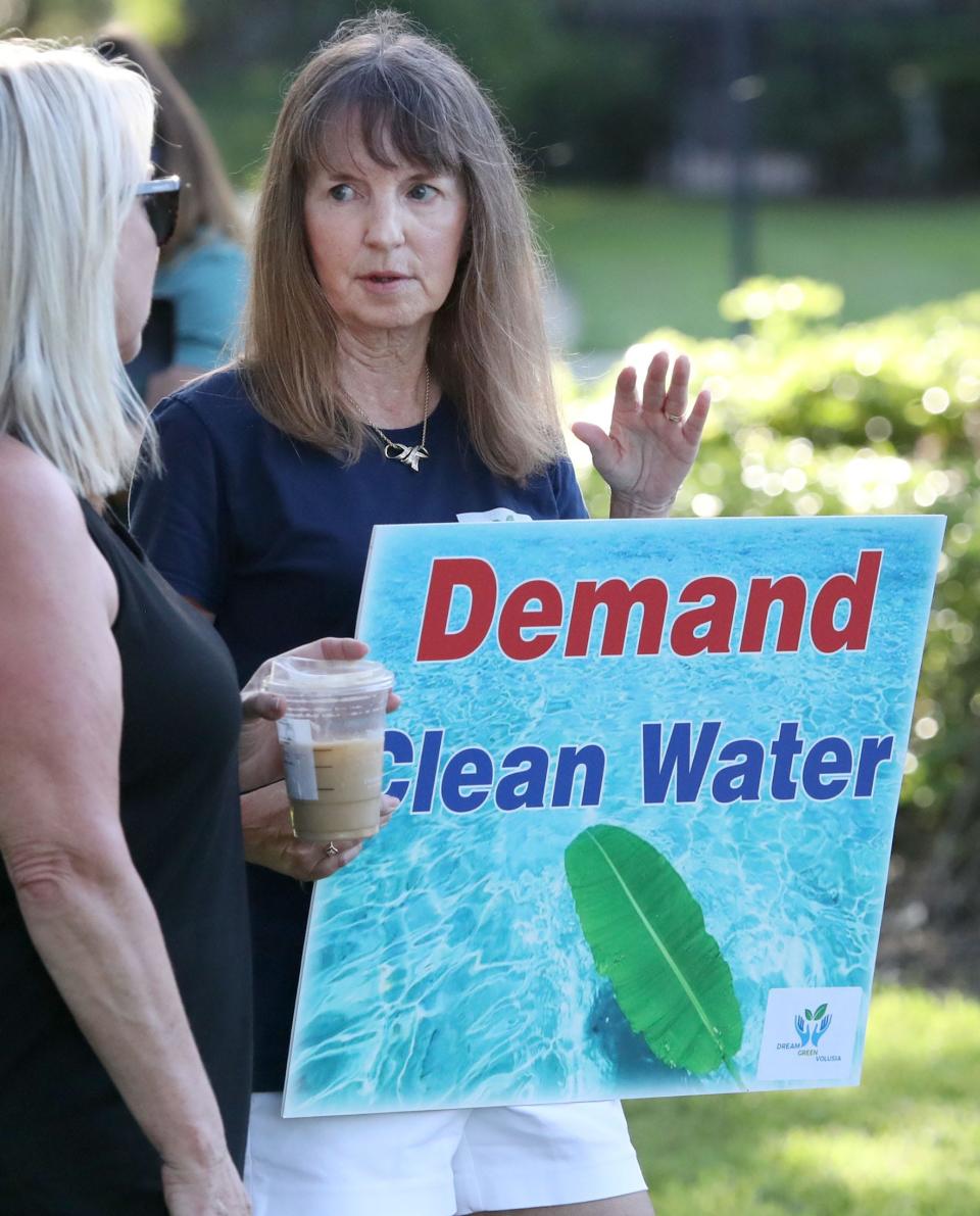 Suzanne Schriber, with Dream Green Volusia, talks with a resident during the demonstration at the lake in the Victoria Lake development in DeLand, Wednesday, July 24, 2024, following wildlife deaths around the popular lake.