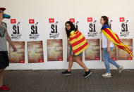 People wear Esteladas (Catalan separatist flags) as they walk past pro independence posters from a youth branch of the leftist Esquerra Republicana de Catalunya (ERC) political party during the regional national day 'La Diada' in Barcelona, Spain, September 11, 2017. REUTERS/Albert Gea