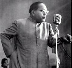 Indian man in suit speaks into microphone