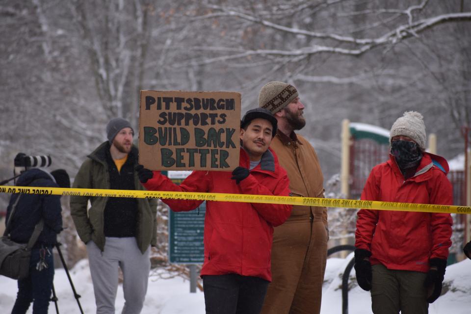 Taiji Nelson holds a sign supporting President Joe Biden's Build Back Better plan at the scene of the Frick Park bridge collapse on Friday.