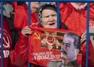 An elderly Russian Communist party supporter holds up a portrait of Soviet dictator Josef Stalin with a Soviet Union sign during a rally in support of Crimea joining Russia near the Red Square in Moscow, Russia, on Saturday, March 22, 2014. Moscow on Friday formally sealed Crimea’s annexation, less than a week after a referendum where Crimeans overwhelmingly voted to join Russia. (AP Photo/Alexander Zemlianichenko Jr)