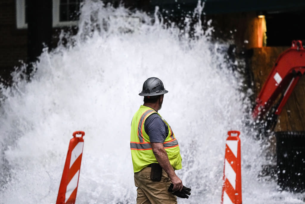 A crew member walks near a broken water transmission line 