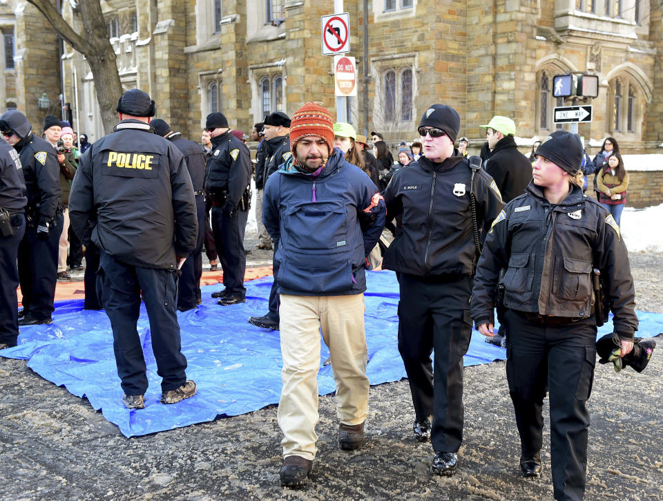 John Lugo, center, of Unidad Latina en Accion of New Haven, is arrested during a demonstration after some protesters blocked the intersection of Elm and College Streets in New Haven, Conn., Friday, Feb. 10, 2017, and refused to move. The protesters are in favor of changing the name of Yale University's Calhoun College. The peaceful arrests were pre-planned and coordinated between the demonstrators and New Haven Police. (Peter Hvizdak/New Haven Register via AP)