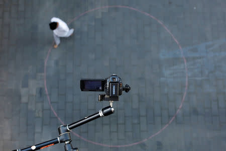 A camera films Chinese performance artist Hua Weihua as he performs his piece "Circle" at the OPEN international performance art festival in the Songzhuang art colony outside Beijing, China, September 22, 2017. REUTERS/Thomas Peter