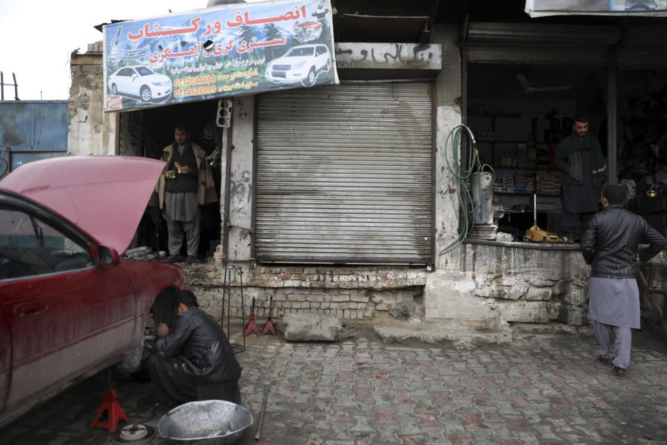 An Afghan mechanic repairs a car in front of the sealed and locked workshop of Abdul Sami, who was arrested and accused of putting a sticky bomb inside the wheel well of a vehicle, in Kabul, Afghanistan, Sunday, March 14, 2021. Sticky bombs slapped onto cars trapped in Kabul’s chaotic traffic are the newest weapons terrorizing Afghans in the increasingly lawless nation. The surge of bombings comes as Washington searches for a responsible exit from decades of war. The primitive devices made for little money, are used by militants, criminals or those trying to settle personal scores. (AP Photo/Rahmat Gul)