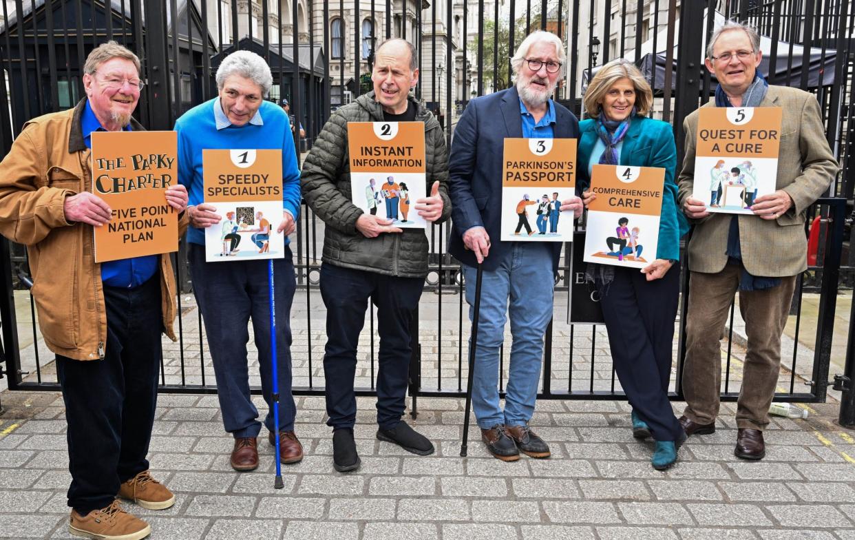 The podcast hosts stand in a row outside Downing Street. Several use walking sticks