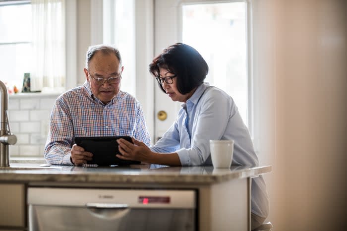 Two people in a kitchen looking at a tablet.