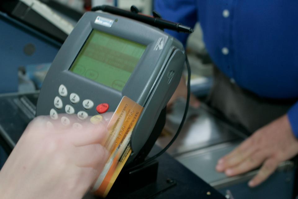 A person swipes a card to make an in-store purchase.