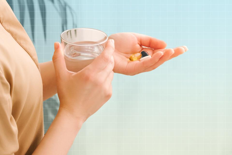 a photo of a hand holding various supplements and the other hand holding a glass of water