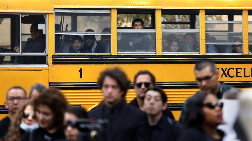 LOS ANGELES-CA-FEBRUARY 27, 2024: A school bus passes by as the Los Angeles County Association of Environmental Health Specialists hold a vigil for their colleague Heather Hughes, who died on Feb. 8 after jumping from the roof of the Koreatown building where she worked for the LA County Department of Public Health's Environmental Health Division as a health inspector, outside the Kenneth Hahn Hall of Administration in downtown Los Angeles on February 27, 2024. (Christina House / Los Angeles Times)