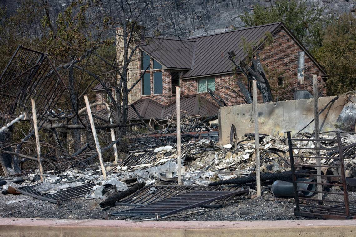 An intact house just behind the remains of a home on Possum Kingdom Lake in Graford, Texas, on Wednesday, July 20, 2022.