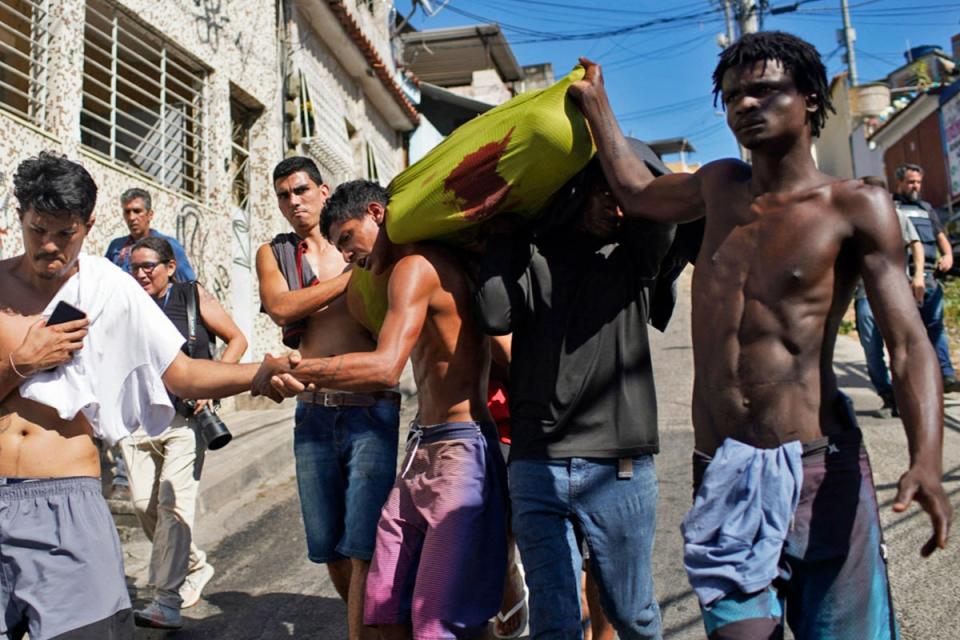 Residents of the Complexo do Alemao favela carry a corpse following a police raid in Rio de Janeiro (AFP via Getty Images)