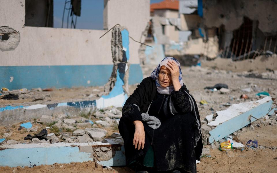 A woman rests next to a damaged building