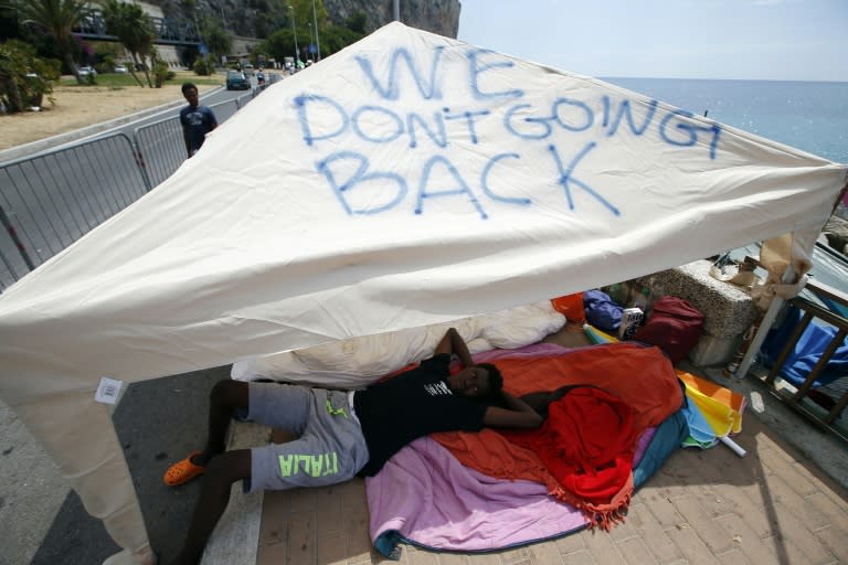 A migrant lies under a tent with the words "We don't going back" written on it in Ventimiglia, Italy at the Italian-French border on June 20, 2015