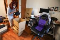 Ines Alcolea places objects inside moving boxes before leaving her rented apartment in Madrid