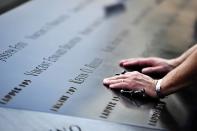 Drew Taylor pauses to remember a New York City Fire Department fire fighter at the South reflecting pool at the 9/11 Memorial during ceremonies marking the 12th anniversary of the 9/11 attacks on the World Trade Center in New York, September 11, 2013. (REUTERS/Stan Honda)