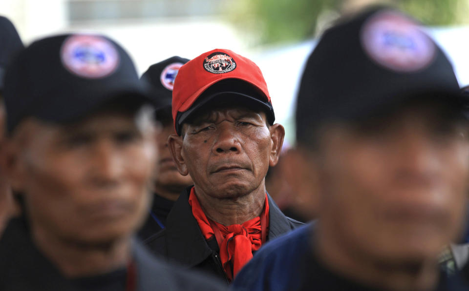 In this April 3, 2014 photo, supporters of Thai Prime Minister Yingluck Shinawatra wait for the start of a Thai kickboxing exercise in Udon Thani province, Thailand. Following the directions of a trainer on a nearby stage, they fended off kicks and practiced footwork to loud speakers blaring music typically heard at a Thai kickboxing stadium. It was was part of a two-day training course for farmers, laborers and others in the heart of pro-government “Red Shirt” country - Thailand’s rural, poor north and northeast. (AP Photo/Sakchai Lalit)