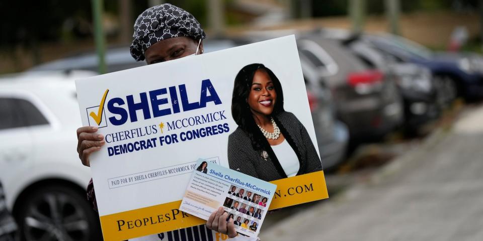 A woman campaigns outside a polling place for Sheila Cherfilus-McCormick, a candidate in the Democratic primary race for Florida's 20th Congressional District seat, in Miramar, Fla., on Election Day, Tuesday, Nov. 2, 2021.