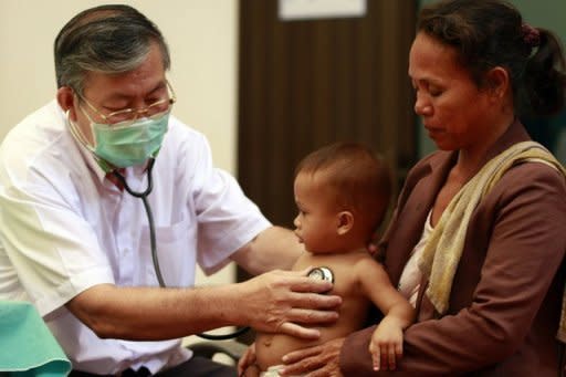 A doctor is seen checking a child at Kantha Bopha children's hospital in Phnom Penh. Health experts working to identify an illness that has killed dozens of children in Cambodia found a link to a virus that causes hand, foot and mouth disease, the UN health agency said on Monday